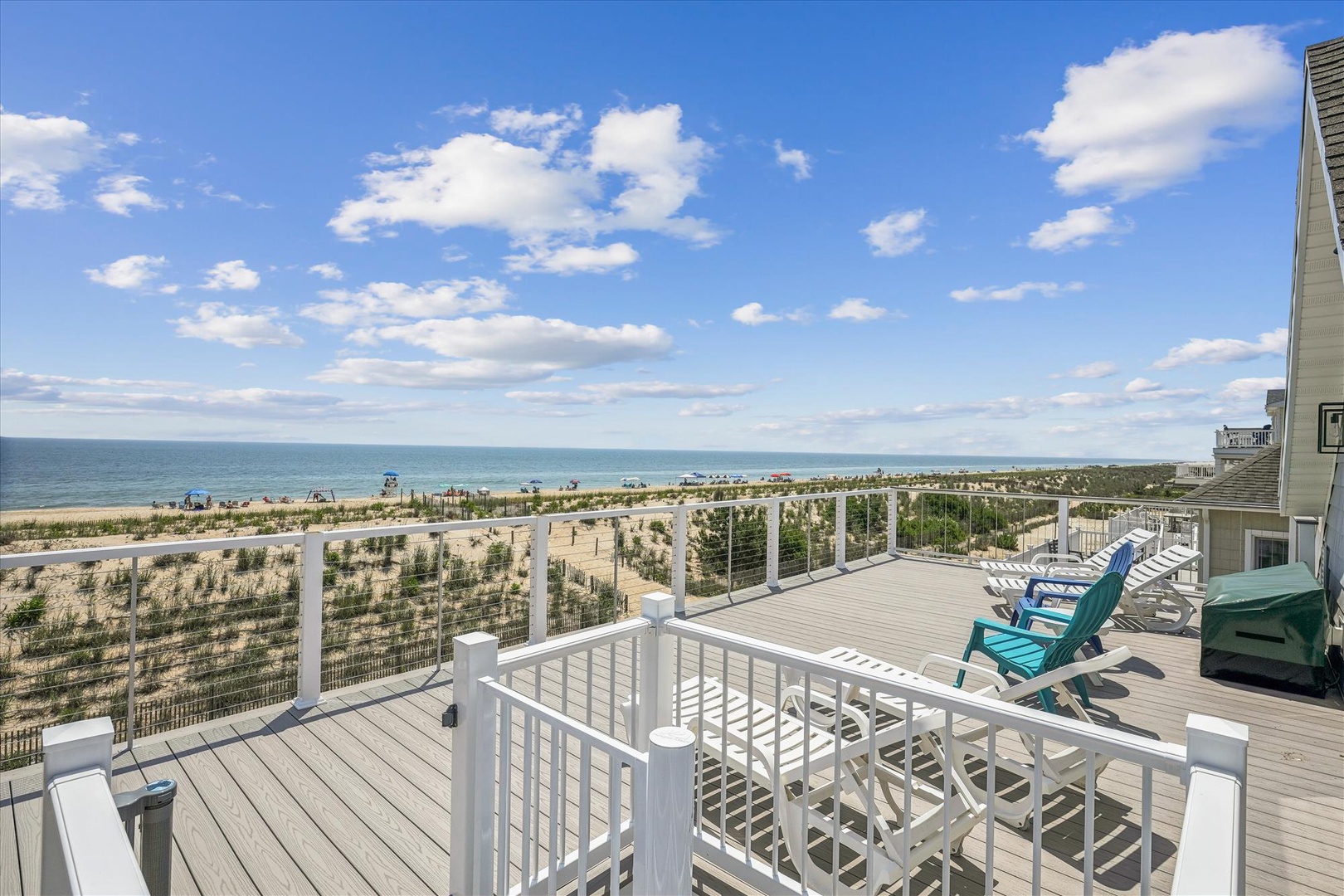 Expansive beachfront deck offering sweeping ocean views, sandy shores, and coastal dunes—an idyllic backdrop for the property's location just steps from the water.