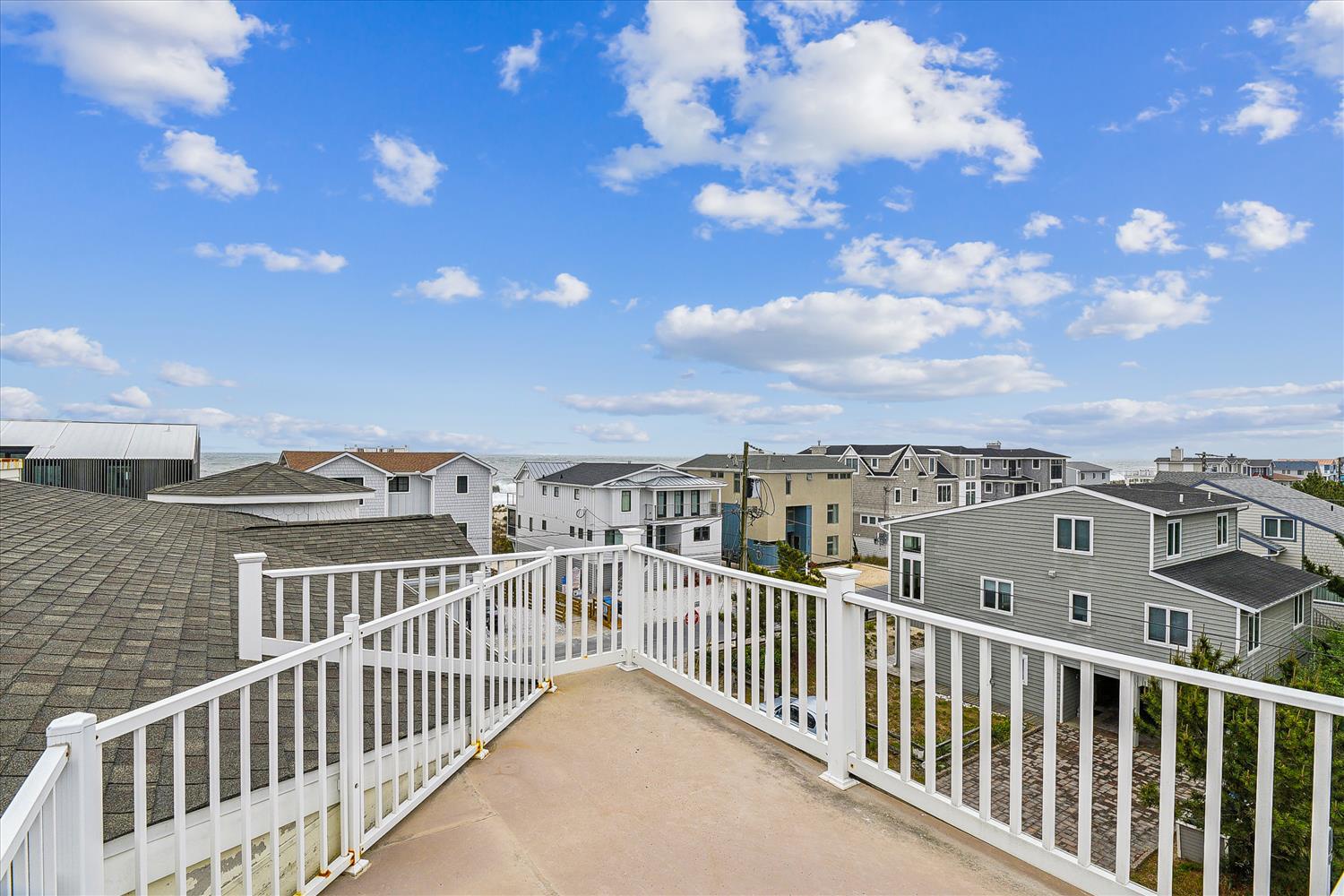 A spacious rooftop deck offering panoramic views of the surrounding residential neighborhood and bright, open skies.