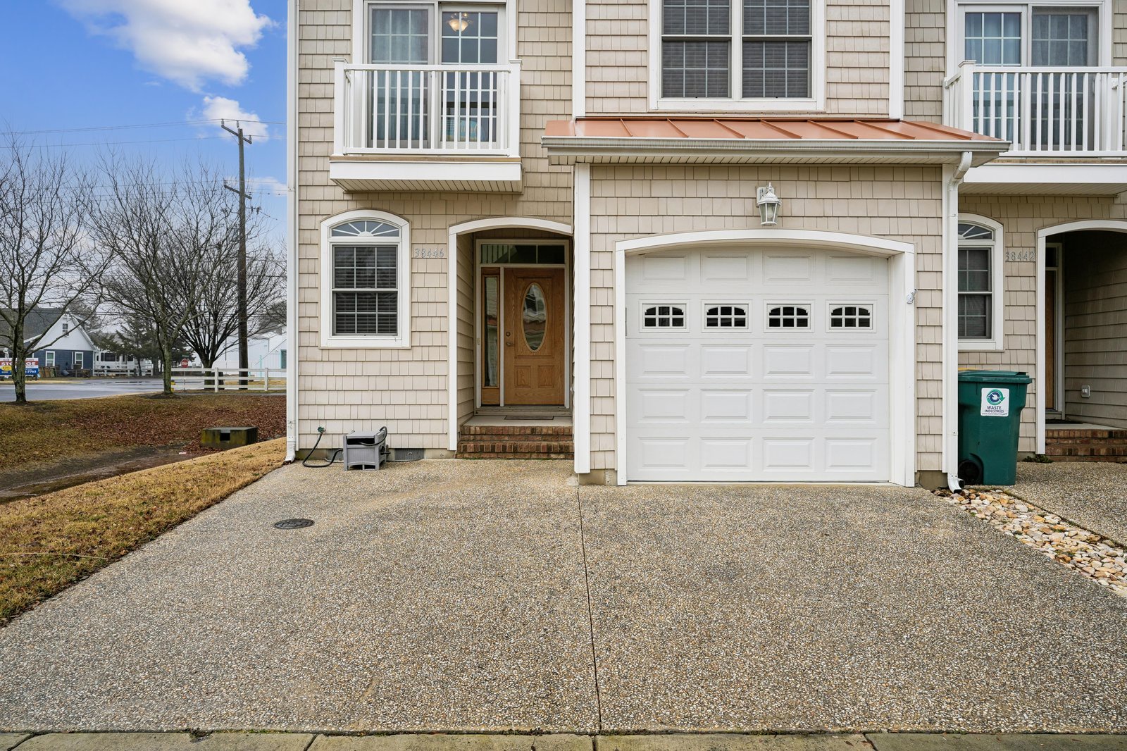 A charming beige-shingled townhome with a private garage and welcoming entrance awaits your arrival in this peaceful residential neighborhood.