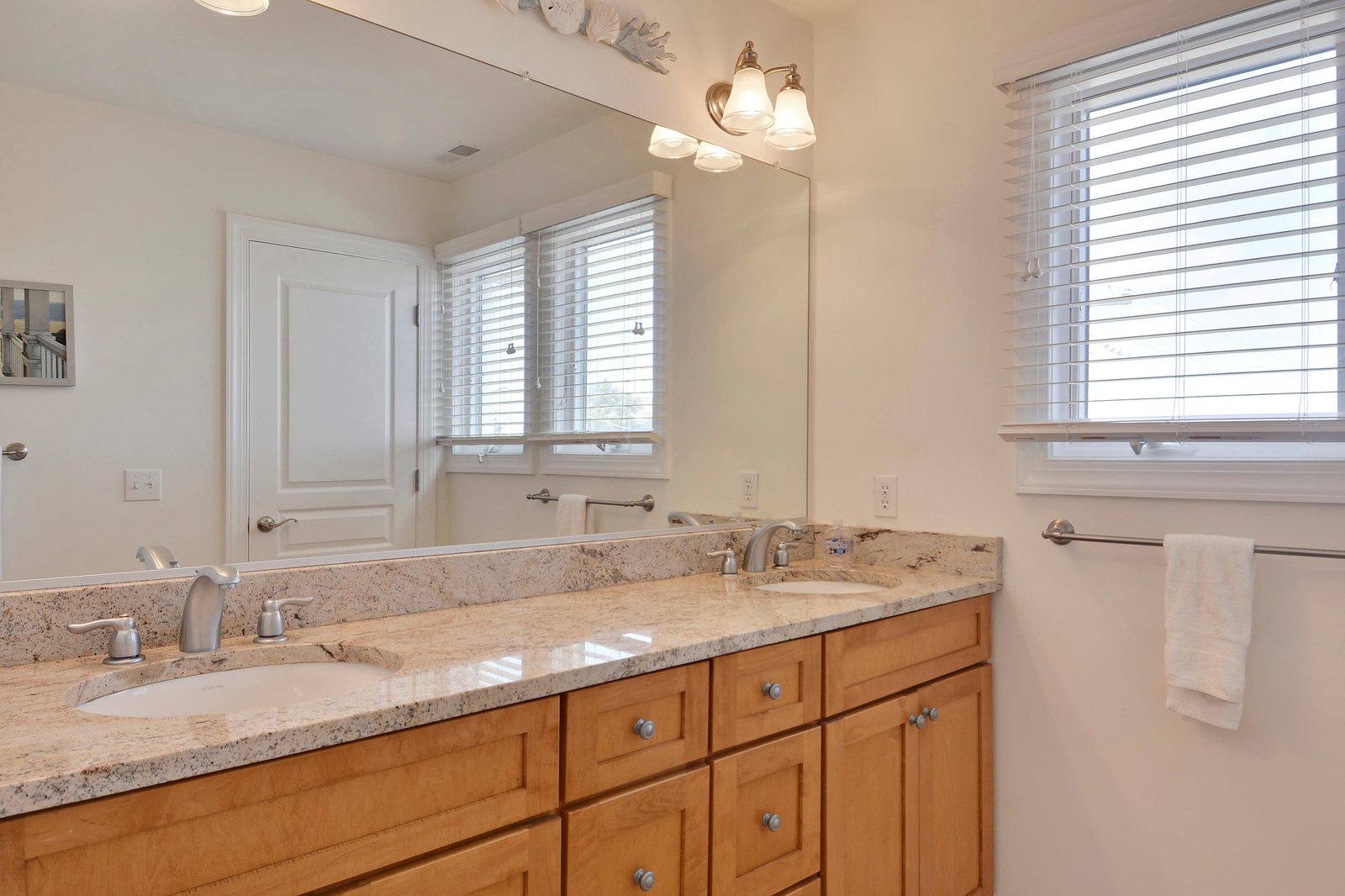 Your private bathroom features a double vanity with granite countertops, abundant natural light, and crisp white linens ready for you.