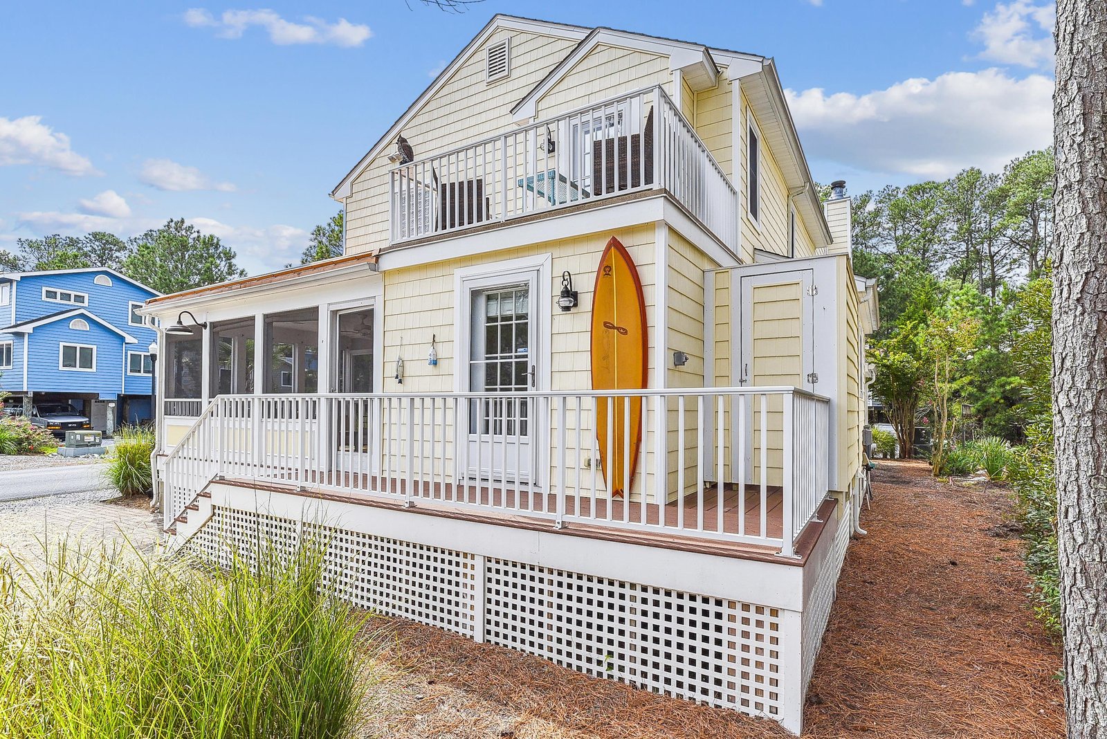 Charming coastal cottage with nautical accents and relaxing screened porch nestled among mature trees in a peaceful neighborhood.