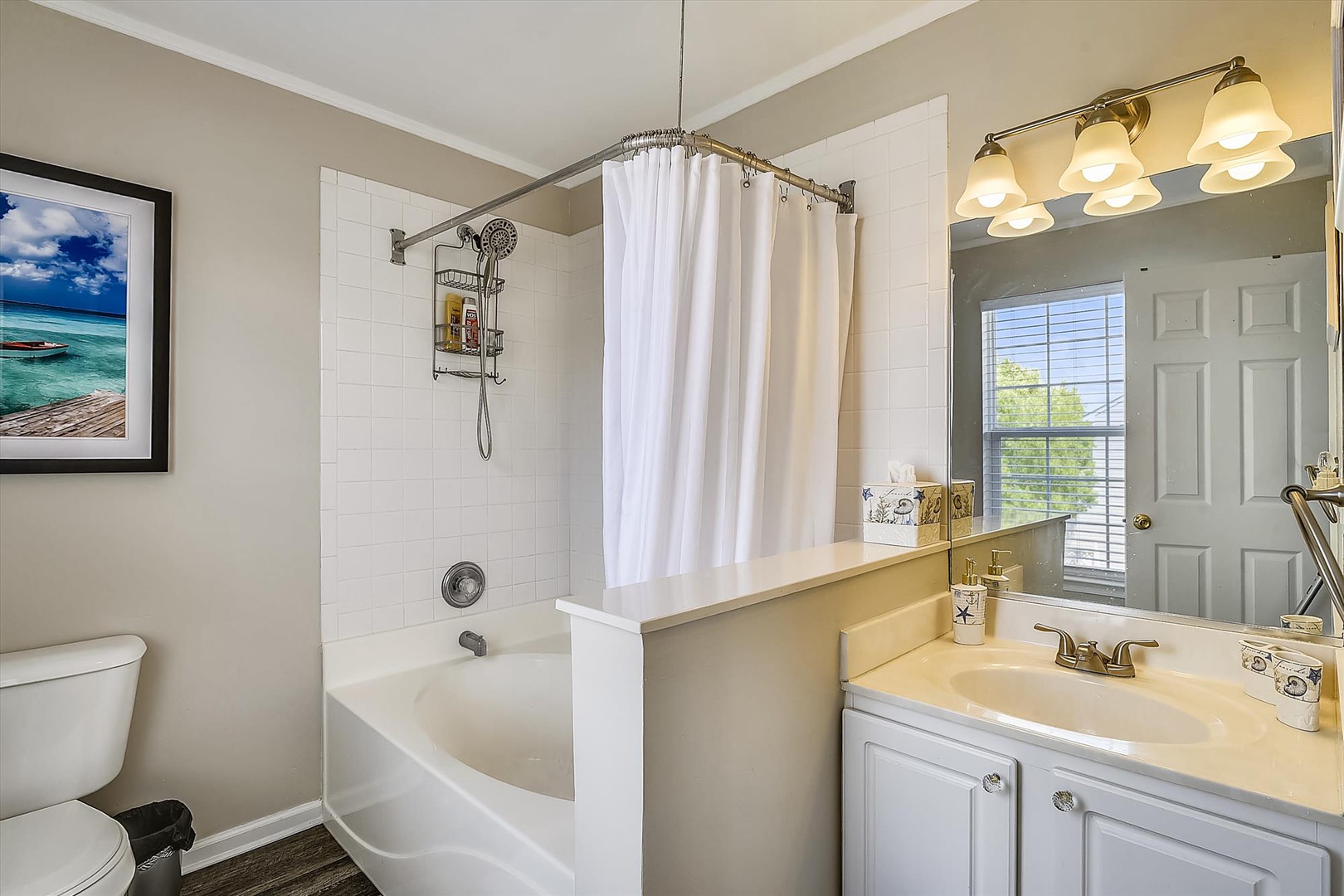 Freshen up in your private bathroom featuring a relaxing soaking tub, white subway tile, bright vanity lighting, and thoughtful coastal touches to make your stay comfortable.