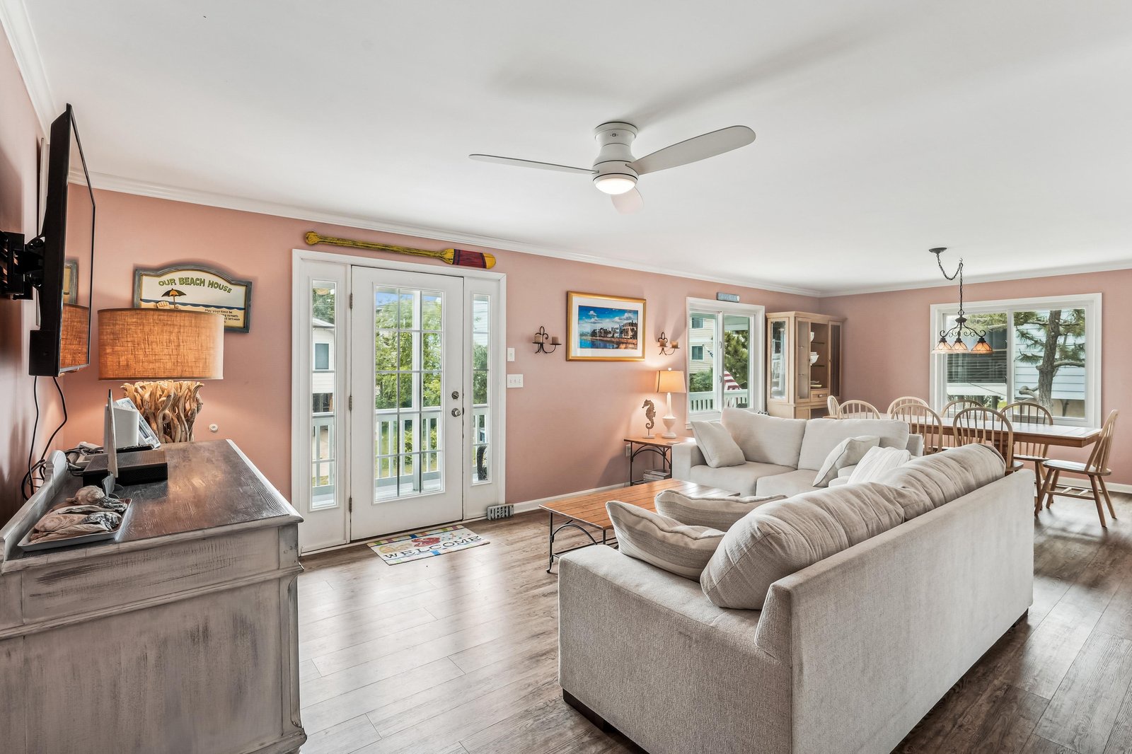 Unwind on plush sofas in this bright living space, where warm coastal tones and French doors invite gentle breezes and natural light into your open-concept retreat.