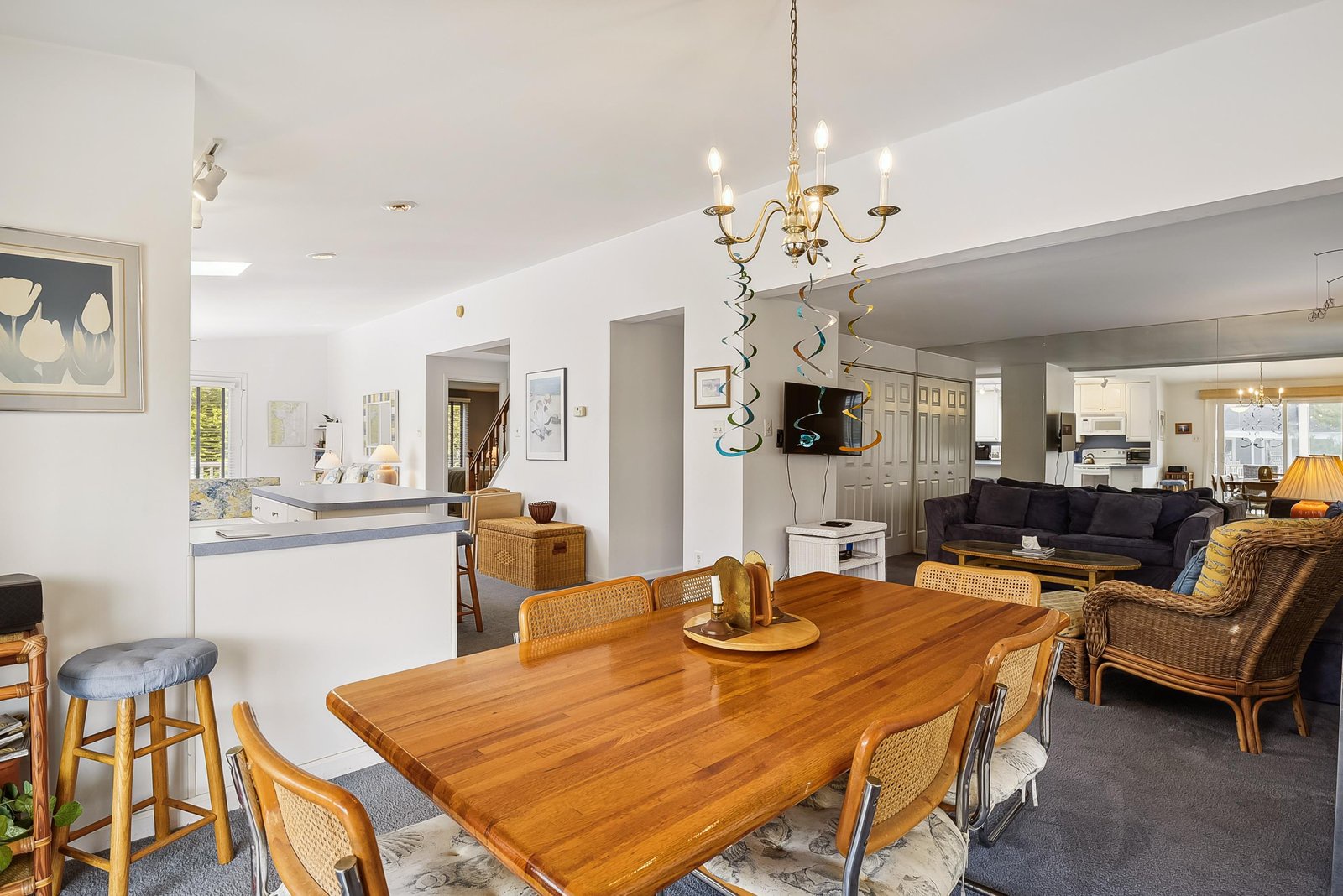 Gather around the warm wood table where conversation flows as easily as light through this open, airy space—your perfect home base for making memories together.