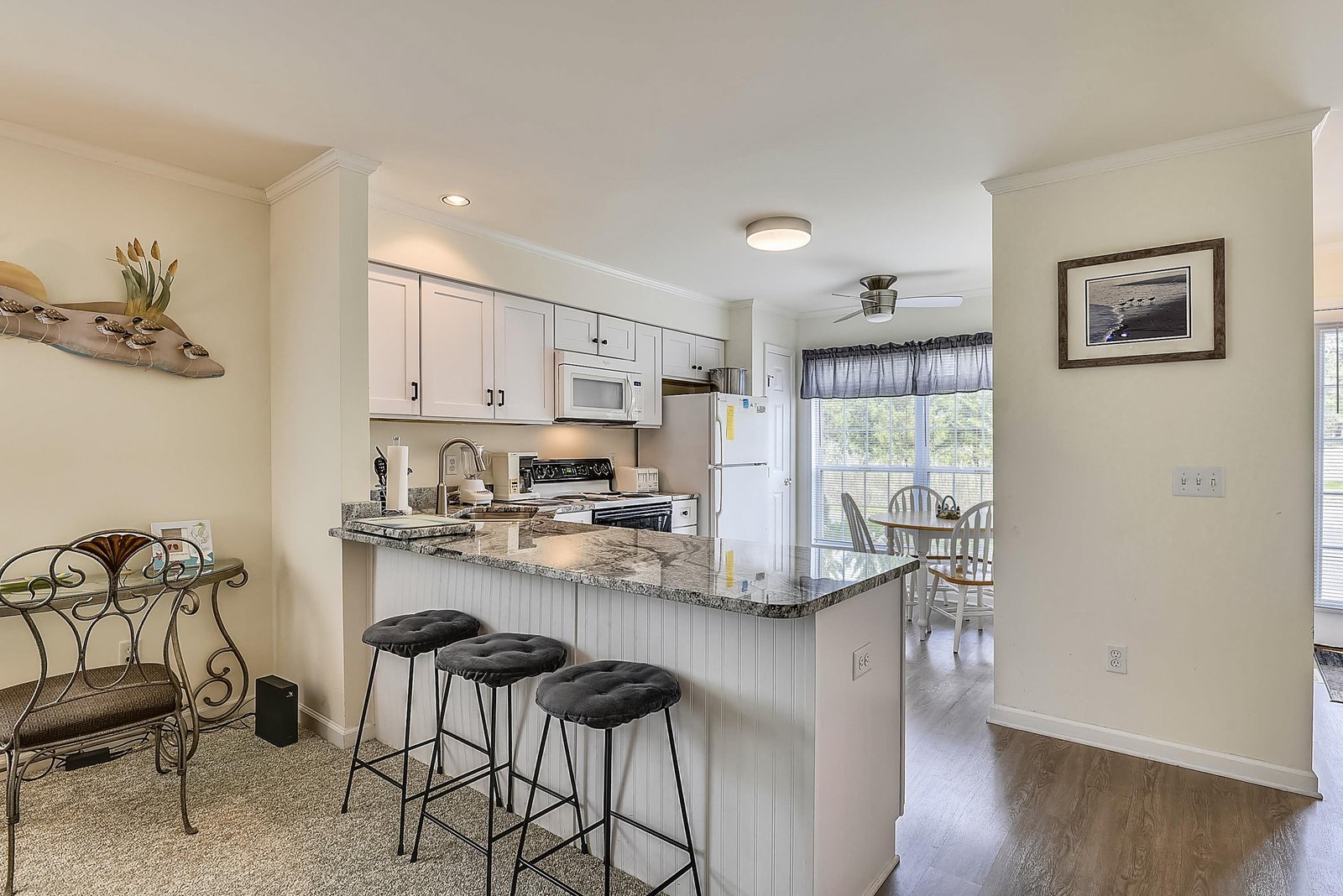 Your open-concept kitchen and dining area invites you to gather and cook with ease, featuring granite countertops, a breakfast bar with seating for three, and natural light streaming in from the dining nook.
