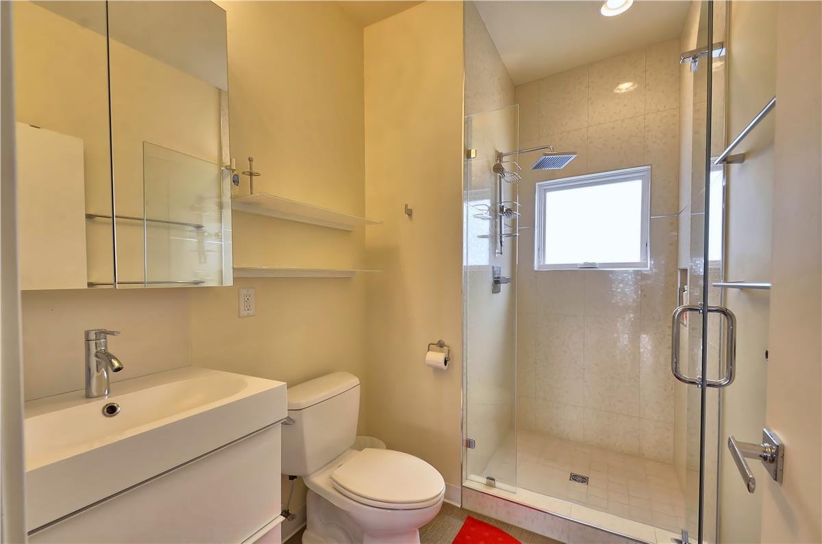 You'll love freshening up in this modern bathroom with its walk-in glass shower, sleek vanity, and bright natural light—every detail designed for your comfort and ease.