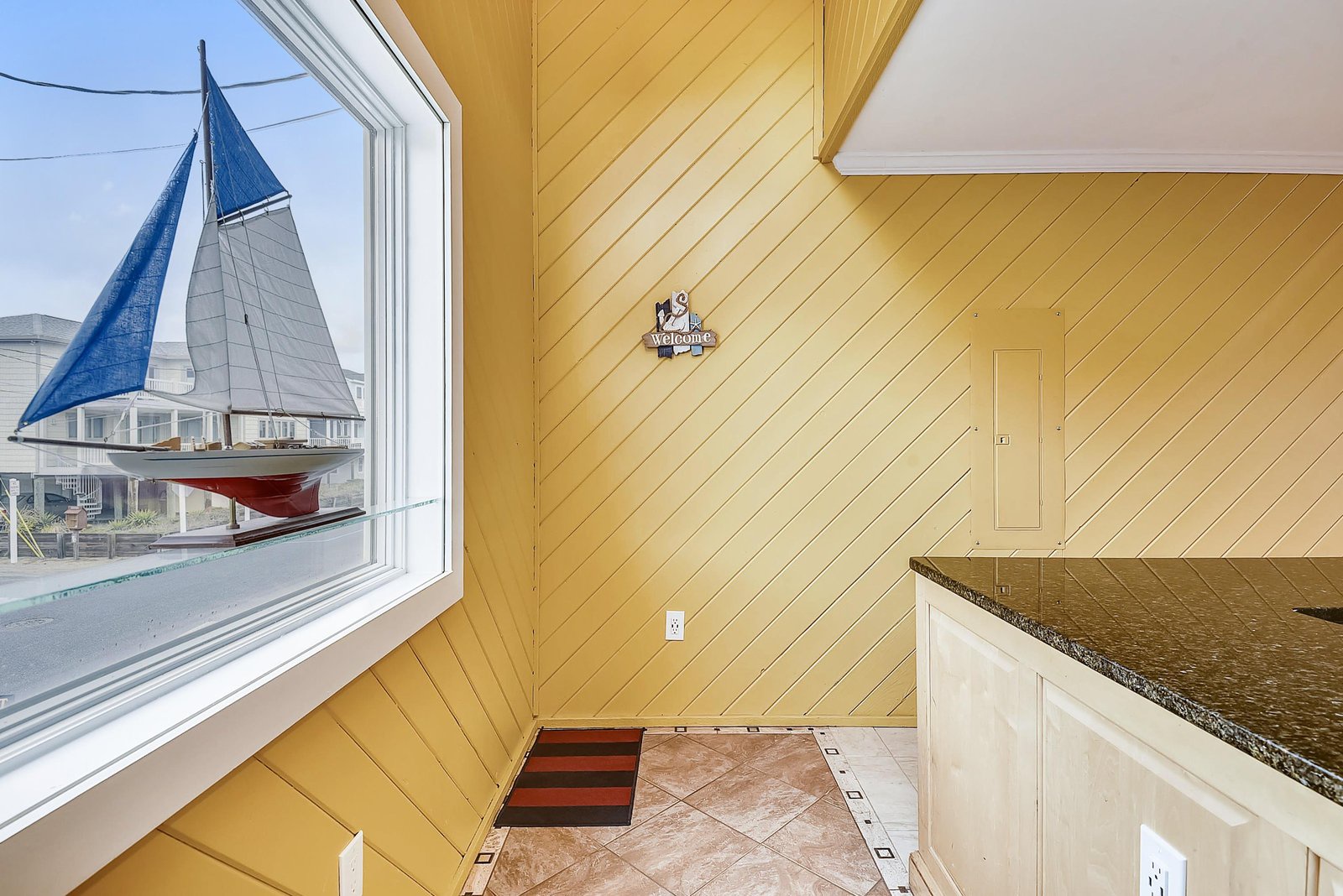 A charming nautical welcome sign and sailboat model greet you in this bright space with warm wood walls and a decorative sailboat display in the window.
