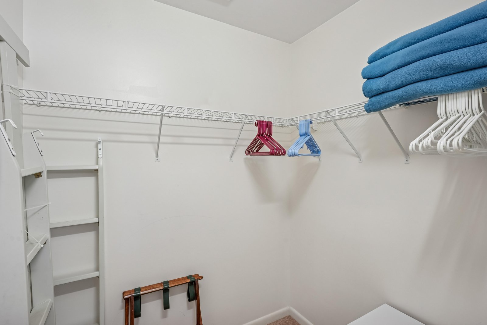 Your spacious walk-in closet offers abundant storage with wire shelving, hanging rods, and a bench for easy unpacking and organization during your stay.