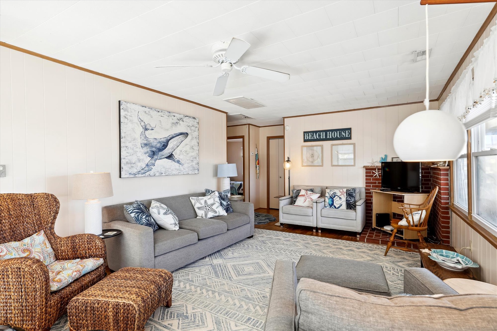 Unwind in your spacious coastal living room, where beachy décor, plush seating, and a charming brick fireplace create a welcoming retreat for relaxing after seaside adventures.