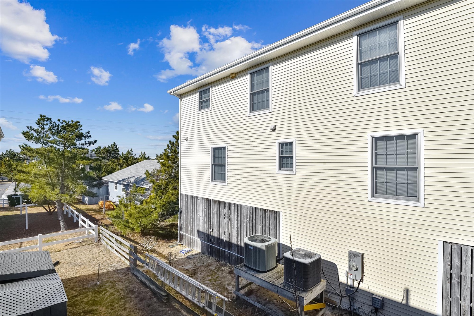 A coastal residential neighborhood with comfortable beach houses surrounded by mature pine trees and nearby rental properties.