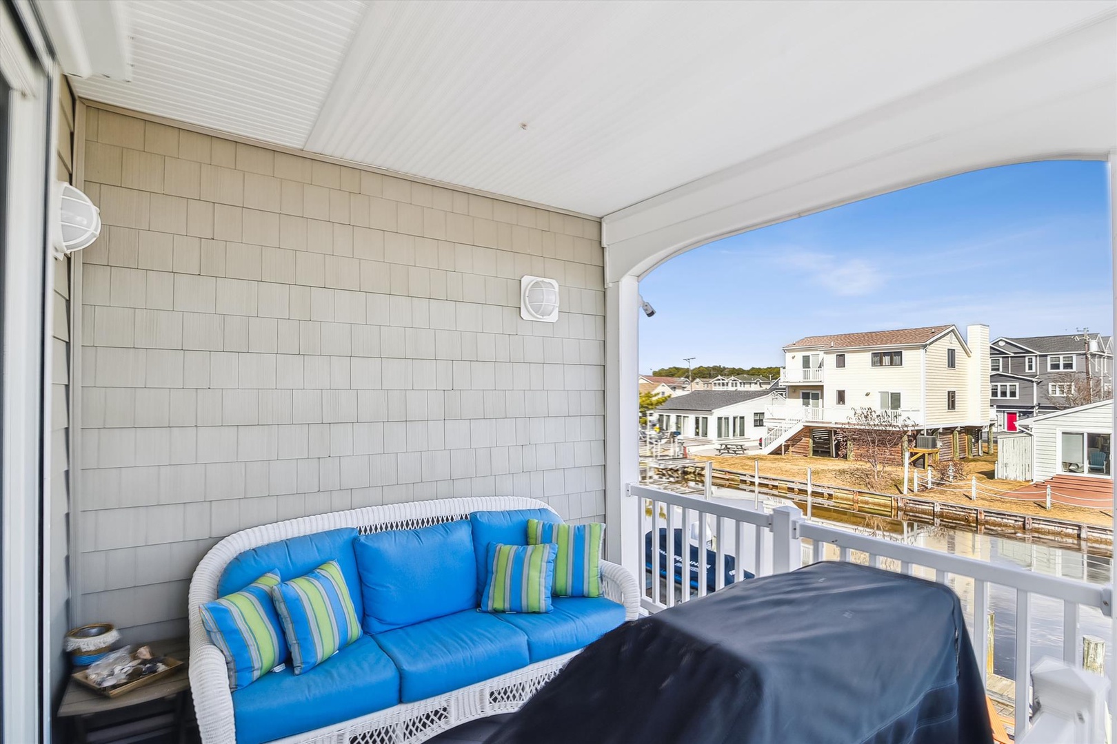 Unwind on your private balcony with vibrant blue seating, where coastal breezes and peaceful neighborhood views create your perfect outdoor retreat.