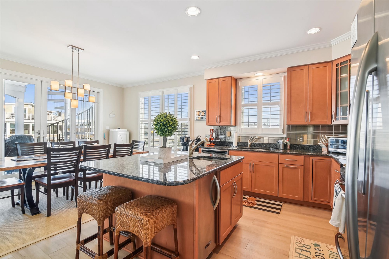 Picture yourself preparing meals in this bright, well-appointed kitchen with gleaming granite counters, stainless steel appliances, and plenty of cabinet space. The center island invites casual dining while natural light pours through plantation shutters.