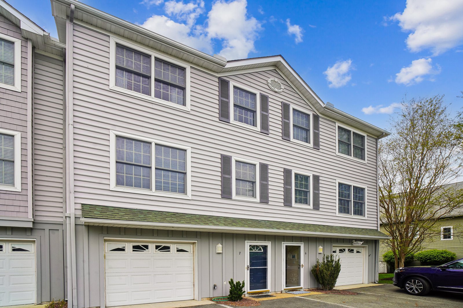 A spacious two-story townhome with classic siding, welcoming garage entry, and modern windows—nestled in a quiet residential neighborhood perfect for your coastal getaway.