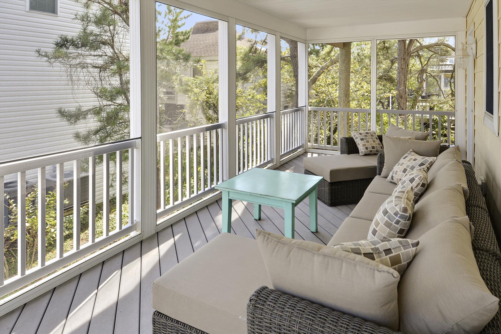 Enclosed porch with wicker seating, a pop of color from the teal table, and tree-lined views to help you unwind in your own tranquil retreat.