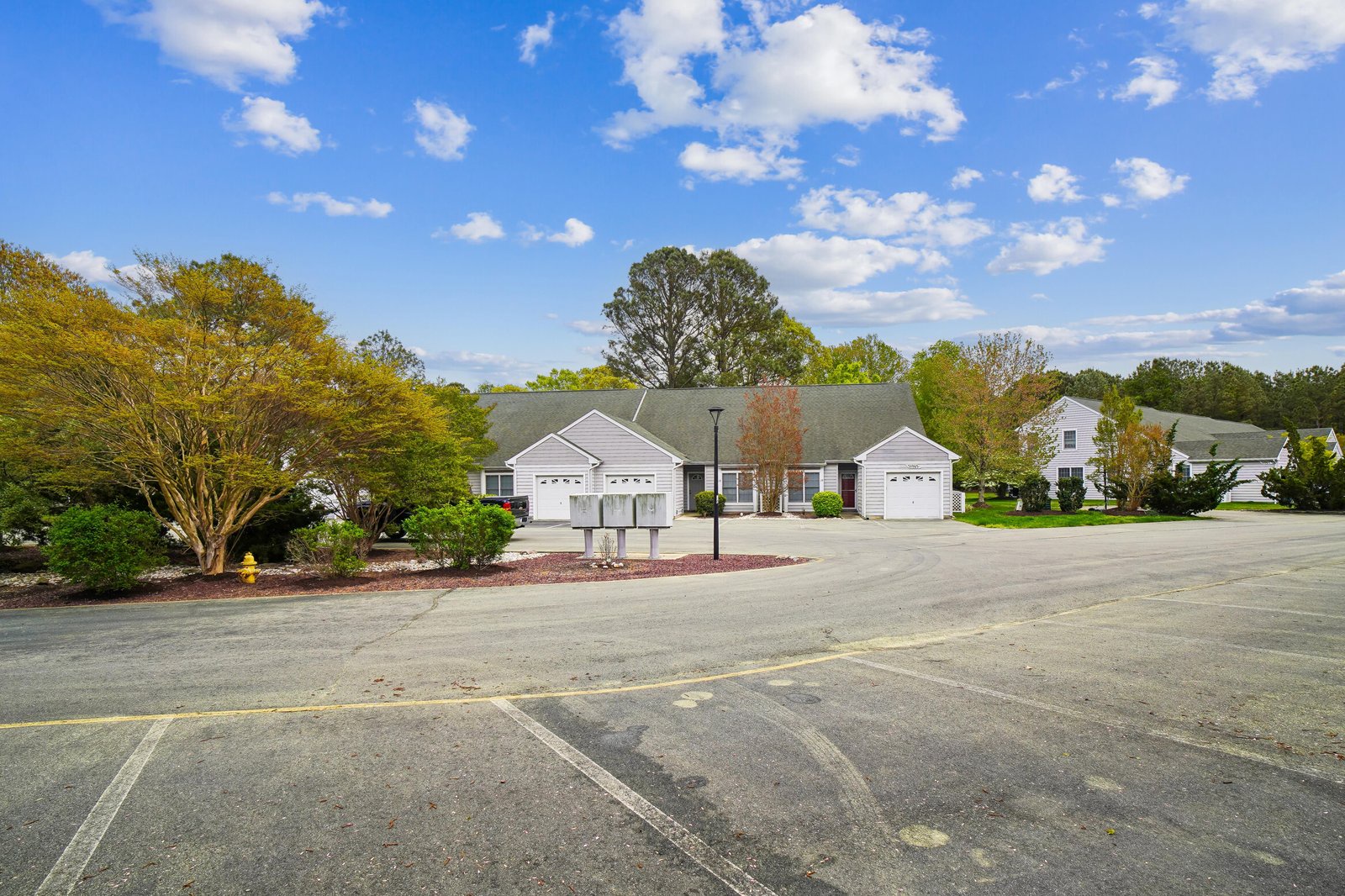 A quiet residential setting with landscaped grounds and garage parking, located in a peaceful neighborhood surrounded by mature trees and open skies.