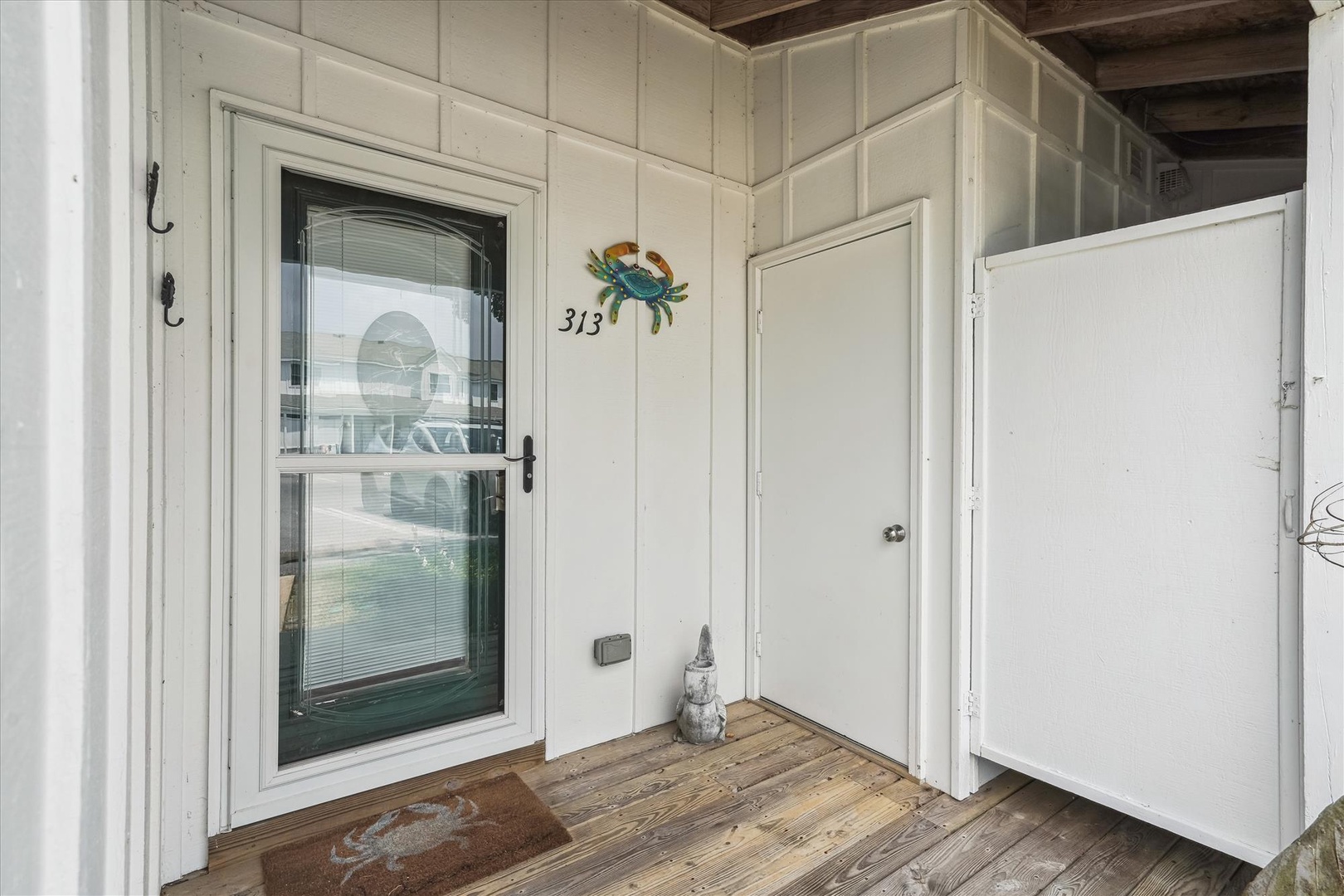 Charming coastal entrance at unit 313 features weathered wood decking and nautical crab decor, welcoming you to your waterfront retreat.