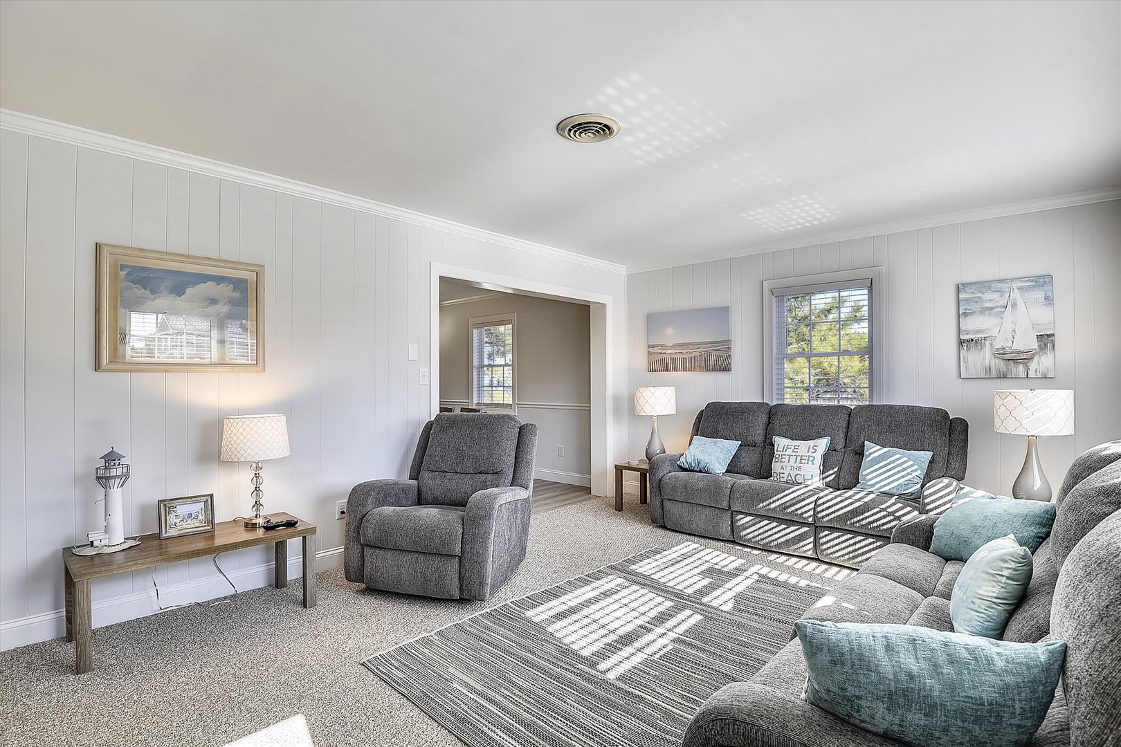 Settle into plush recliners and a spacious sofa in your bright, airy living room. Coastal touches and soft natural light create the perfect retreat.