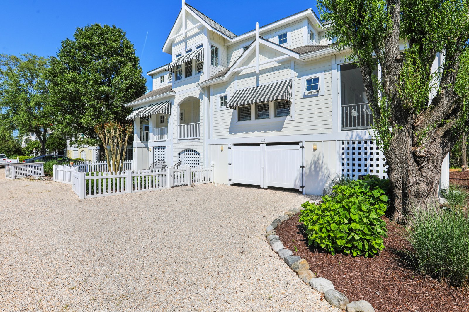 This charming coastal home welcomes you with its classic white exterior, mature shade trees, and well-maintained landscaping—a peaceful retreat in a scenic seaside neighborhood.