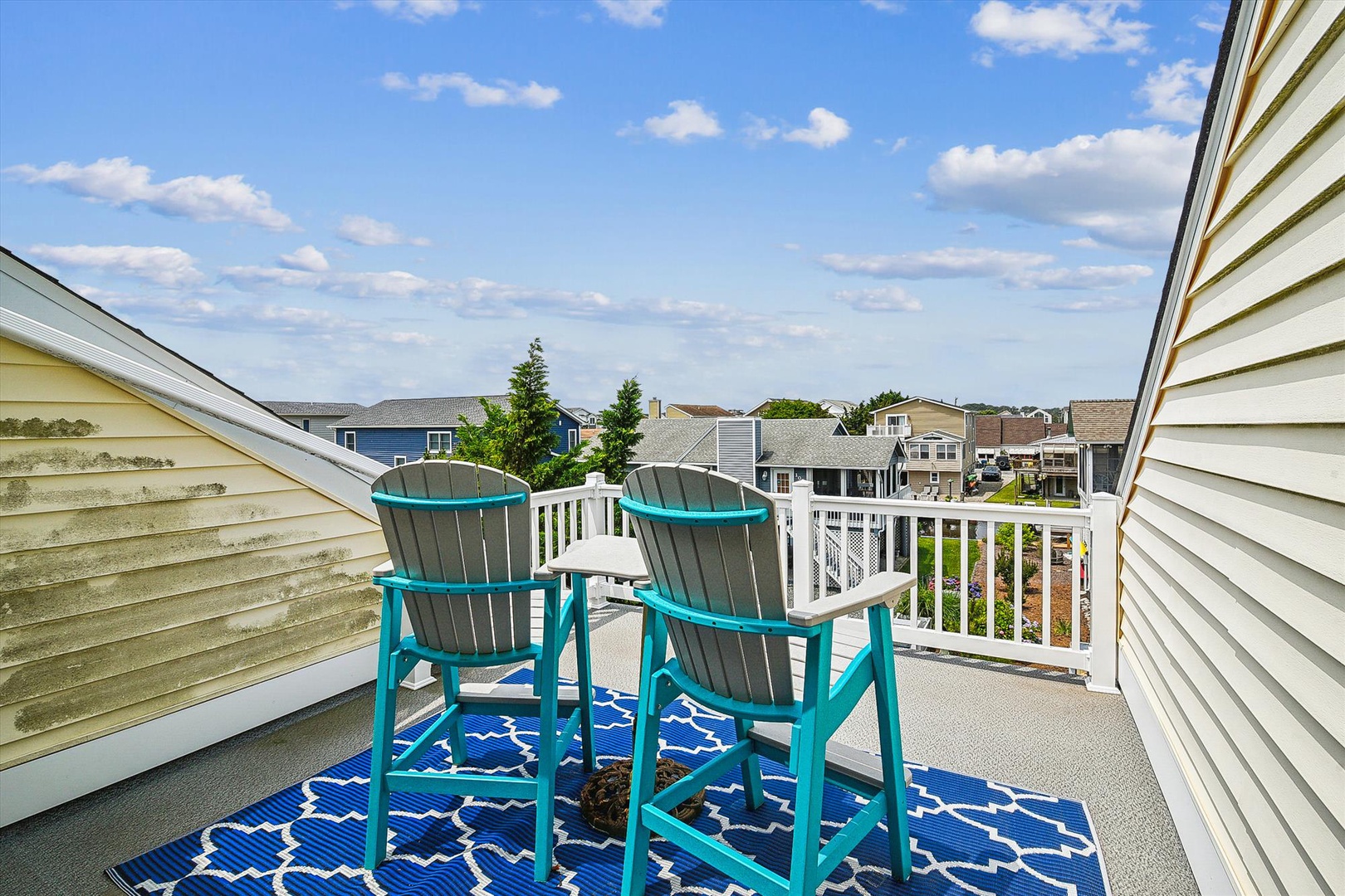 Settle into your private balcony with vibrant turquoise chairs and soak in peaceful neighborhood views under sunny skies—perfect for morning coffee or evening relaxation.