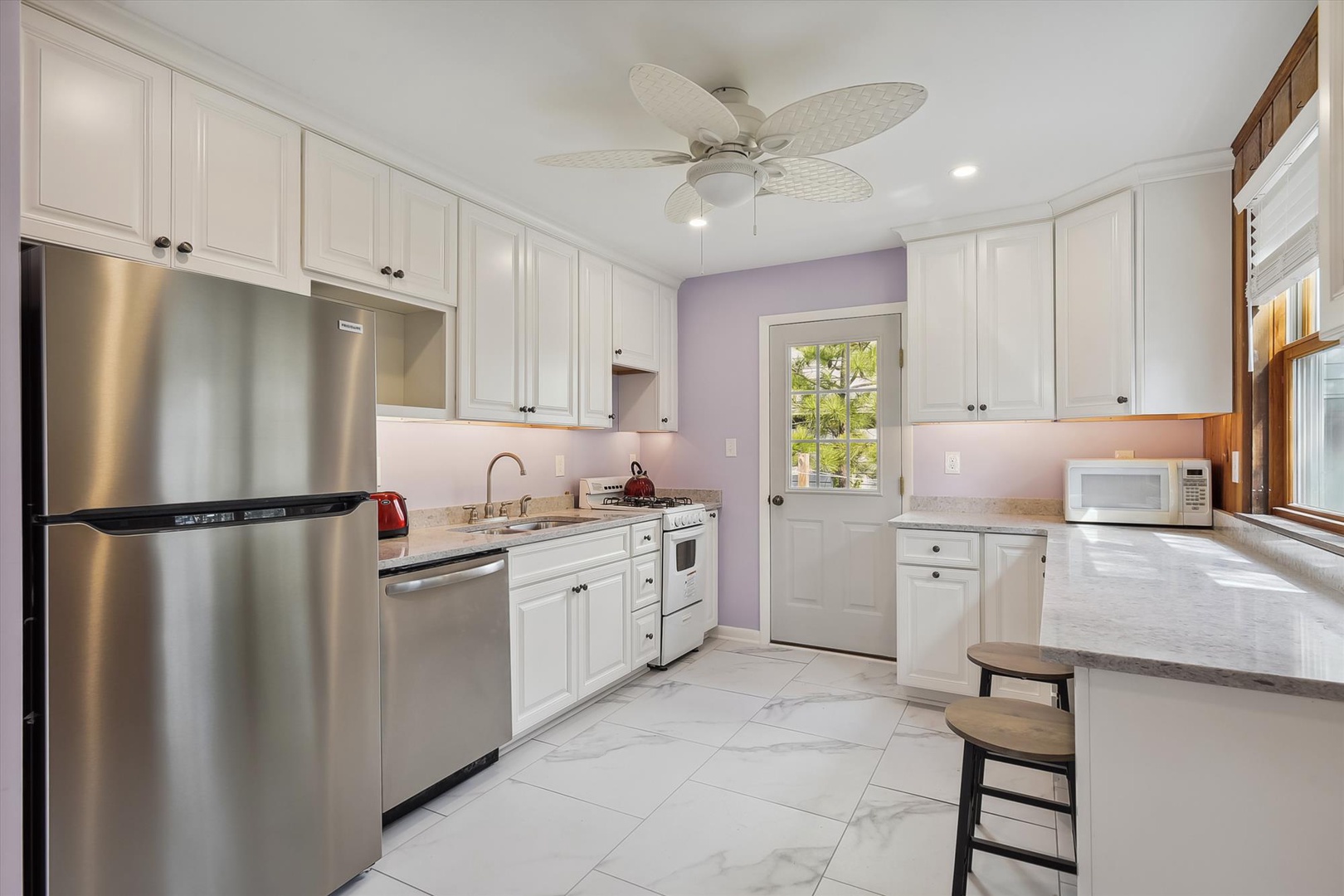 A welcoming space where you'll love preparing meals—crisp white cabinetry, stainless-steel appliances, and breezy ceiling fan create a fresh, airy retreat for cooking and gathering with loved ones.