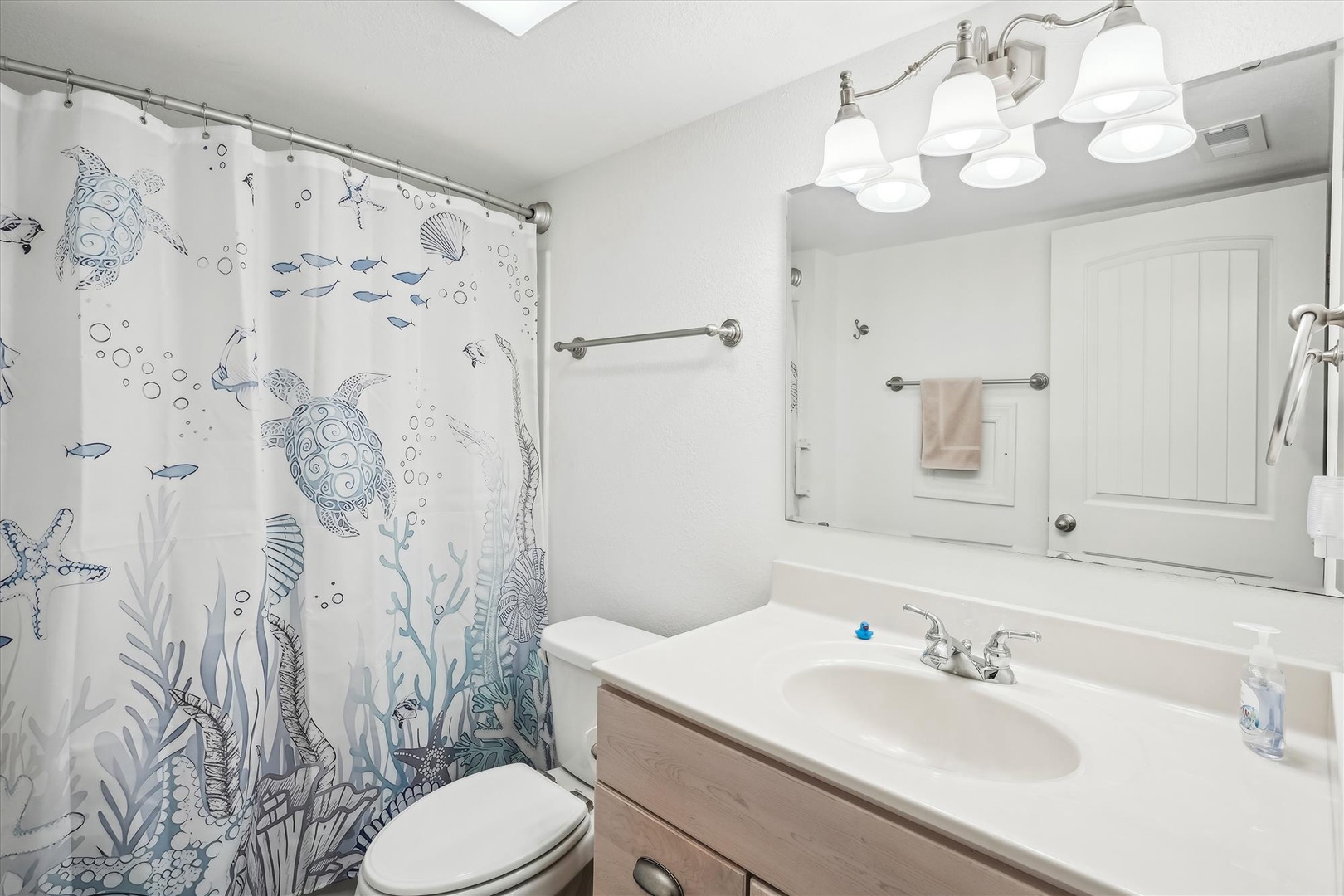 Your private bathroom features charming coastal décor, bright lighting, and fresh towels—step out of the shower and feel refreshed in this welcoming space.