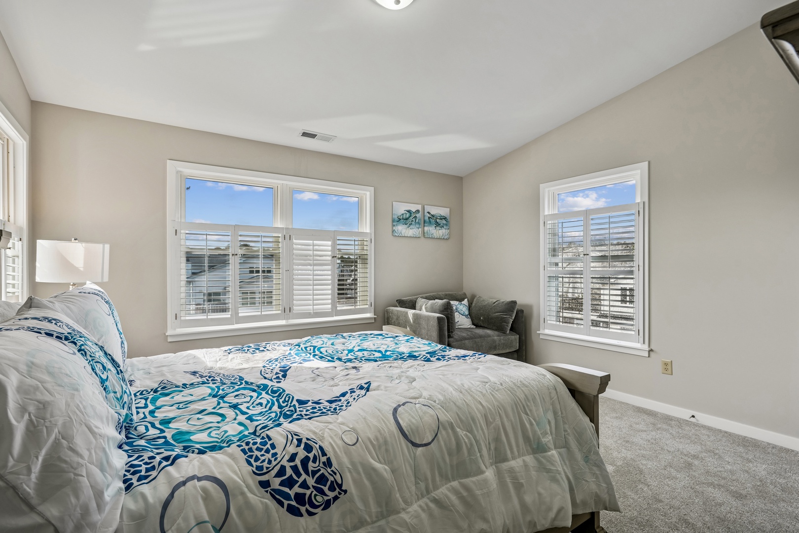 Wake up in your serene bedroom with coastal-inspired bedding and comfortable seating nook by sunny windows.