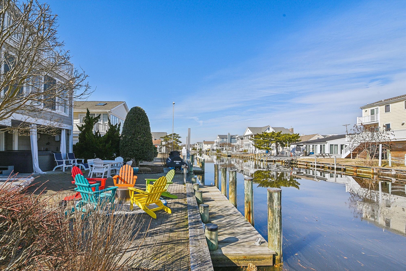 Relax in colorful Adirondack chairs on your private waterfront dock, where peaceful canal views and gentle waters create the perfect escape.
