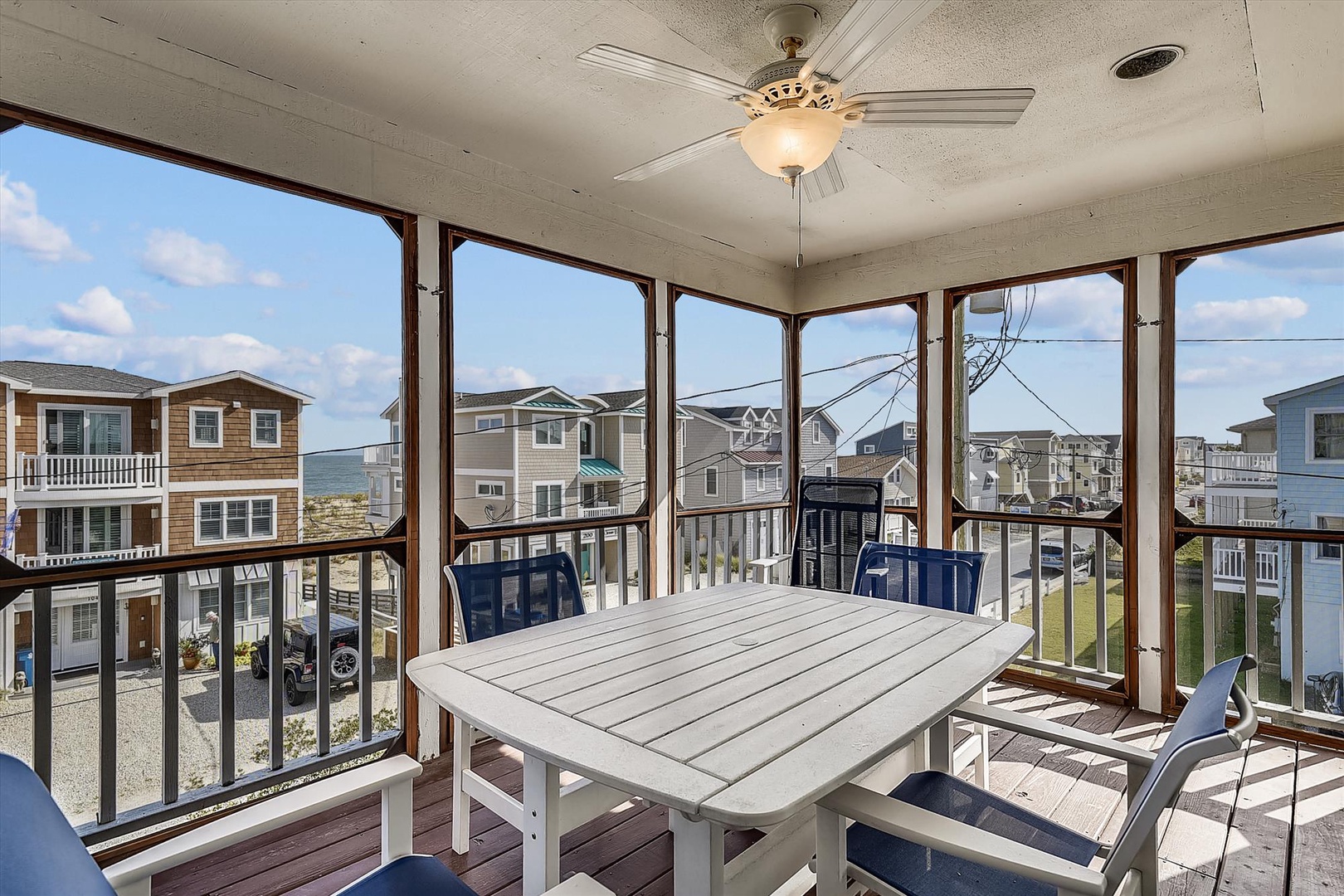 Step into your sunlit screened porch where coastal breezes drift through and blue skies stretch endlessly. Gather around the table, sip morning coffee, and soak in the relaxed rhythm of beachside living.