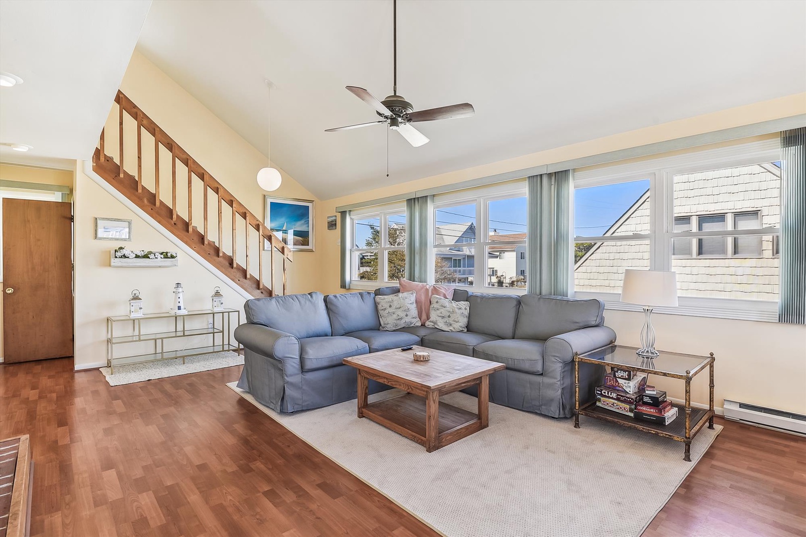 Unwind in your spacious living room with plush seating, warm wood floors, and abundant natural light streaming through large windows. Perfect for relaxing after beach days.