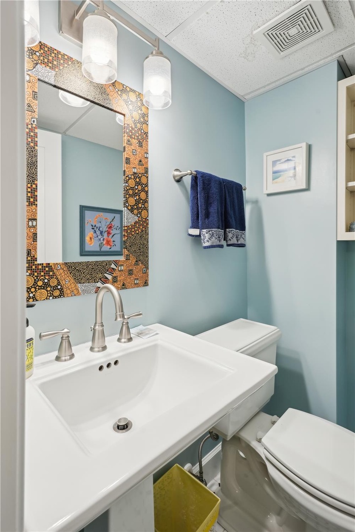 Refresh in this charming bathroom with its vibrant mosaic-framed mirror, crisp blue walls, and stylish vanity—your personal retreat after a day of adventure.