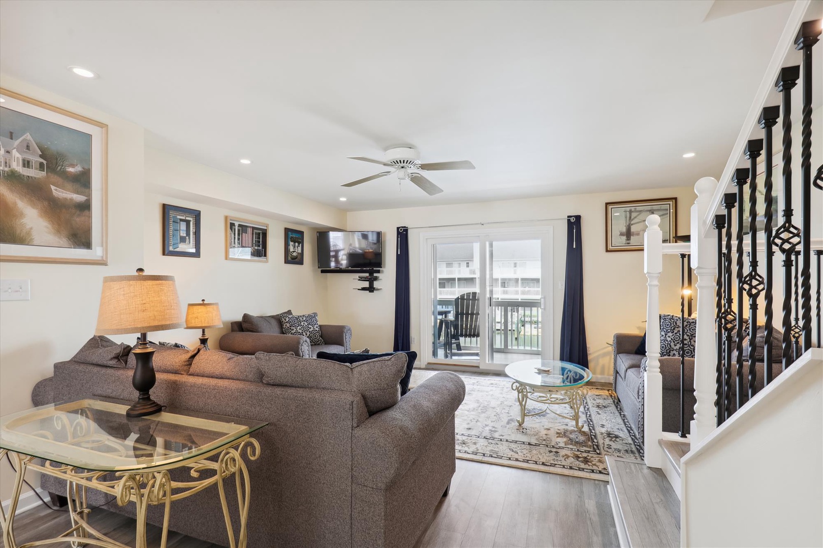 Relax in your inviting living room featuring comfortable sofas, warm lighting, and natural light streaming through French doors leading to your private balcony.