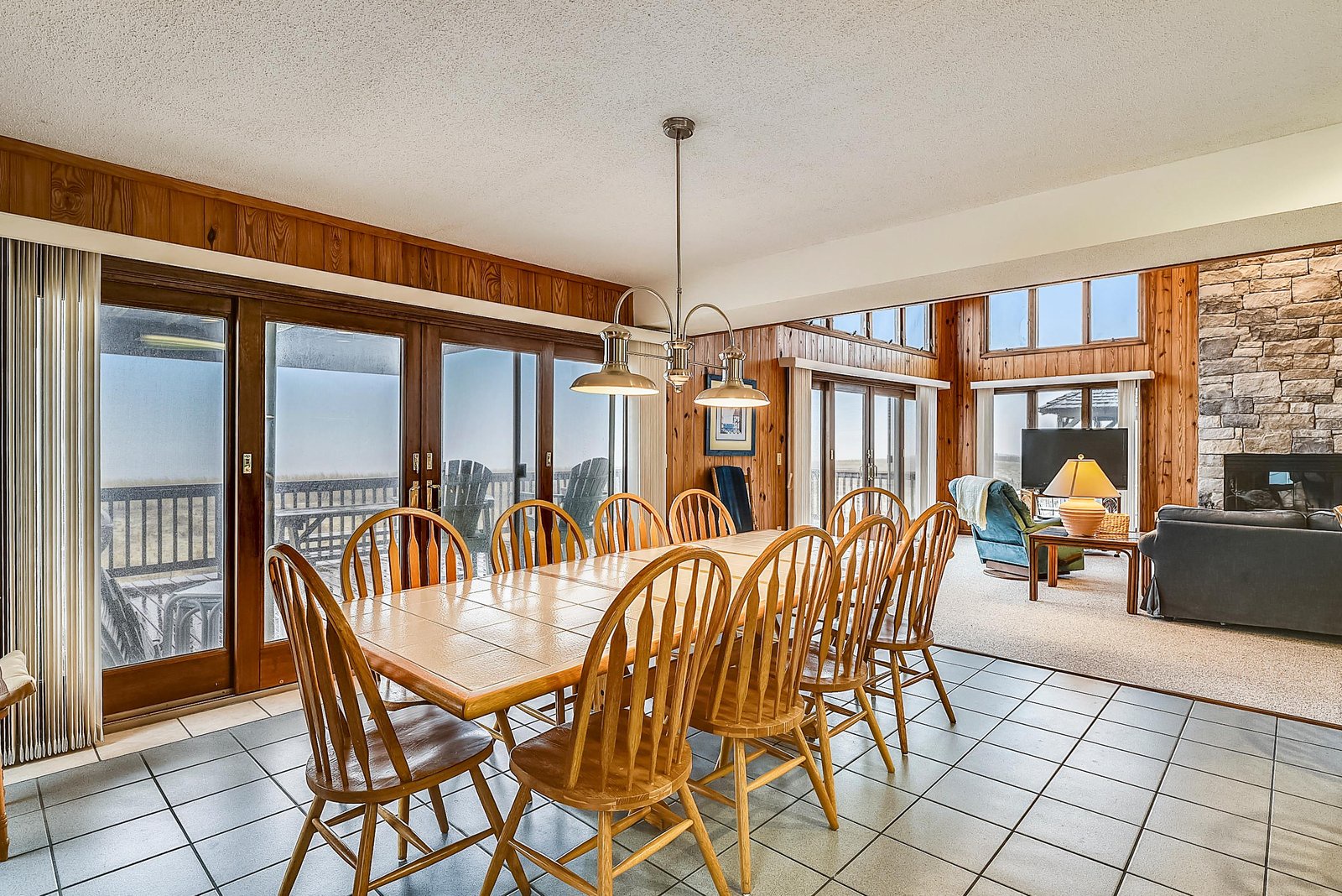 Gather around this spacious dining table with room for everyone, bathed in natural light from the surrounding windows and doors leading to your private deck.