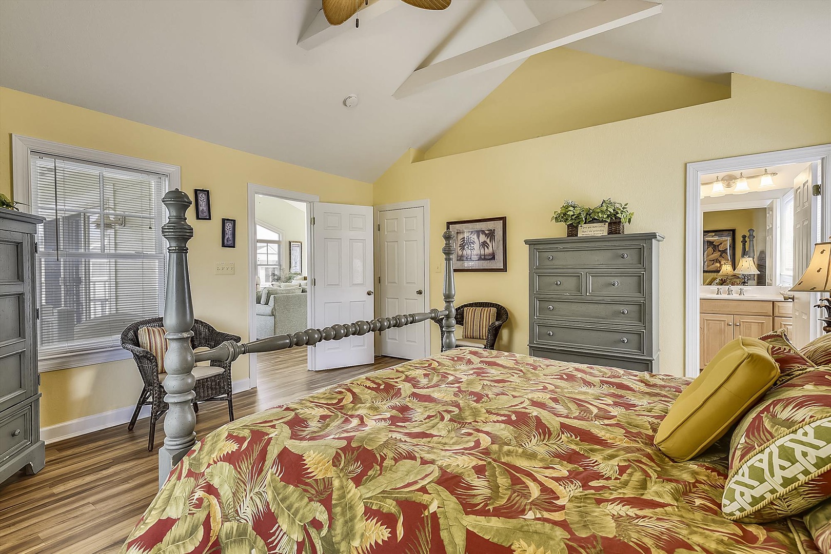 Drift off in your charming bedroom with vaulted ceilings, warm yellow walls, and tropical-patterned bedding that creates a cozy island retreat.