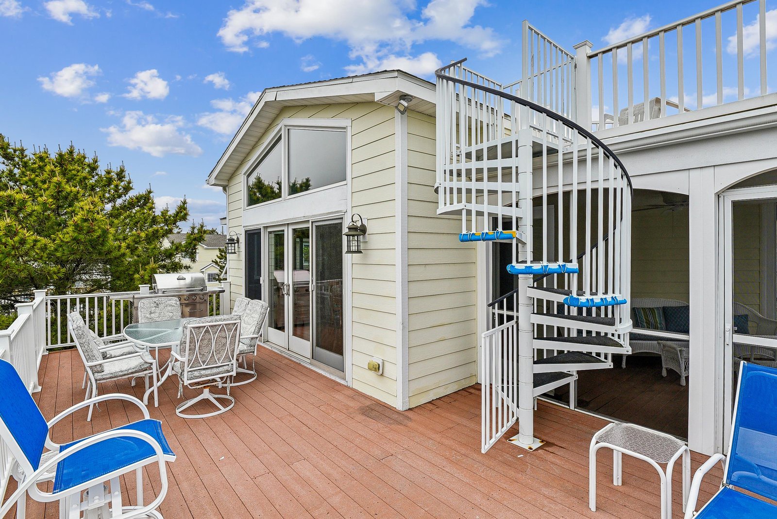 Your rooftop deck offers the perfect spot to unwind under sunny skies, with comfortable seating, a dining table, and a charming spiral staircase leading to even more space to soak in the coastal breeze.
