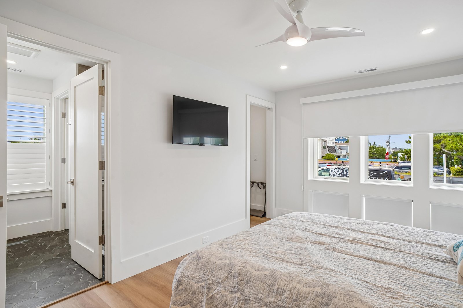 Step into your bright coastal retreat with crisp white walls, a cozy bed, and a ceiling fan to keep things breezy. The TV is ready for your downtime.