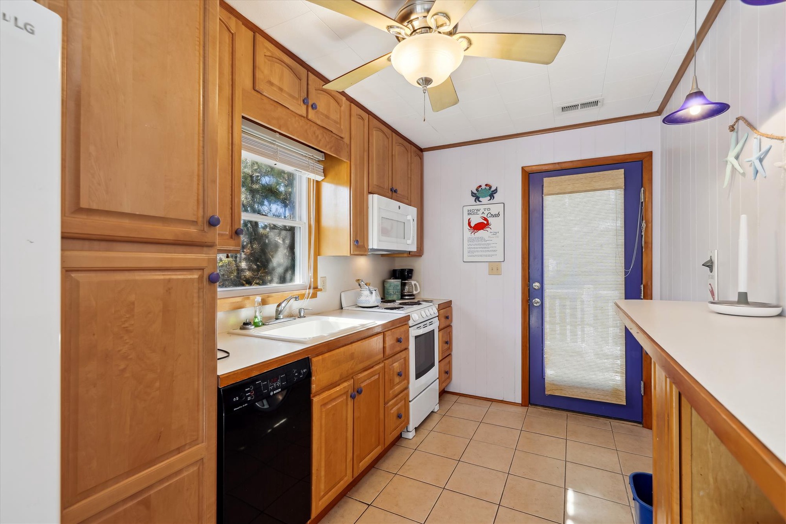A cozy kitchen awaits your culinary adventures, featuring warm wood cabinetry, essential appliances, and a charming coastal vibe with playful nautical touches that make you feel right at home.