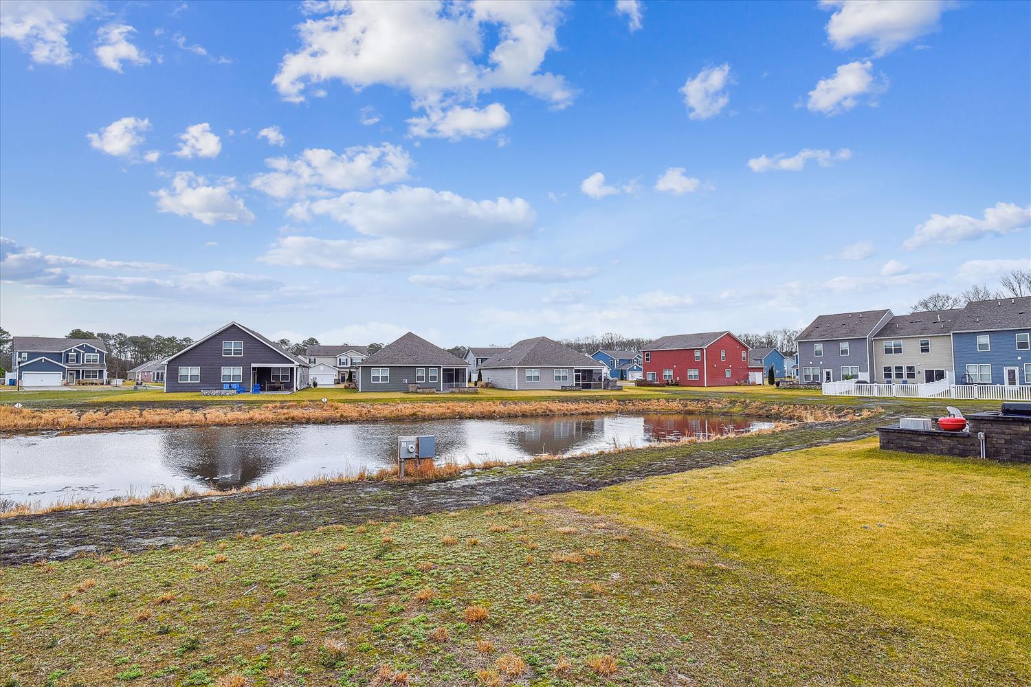 A peaceful residential neighborhood with modern homes lining a tranquil pond, offering serene surroundings in a well-maintained community setting.