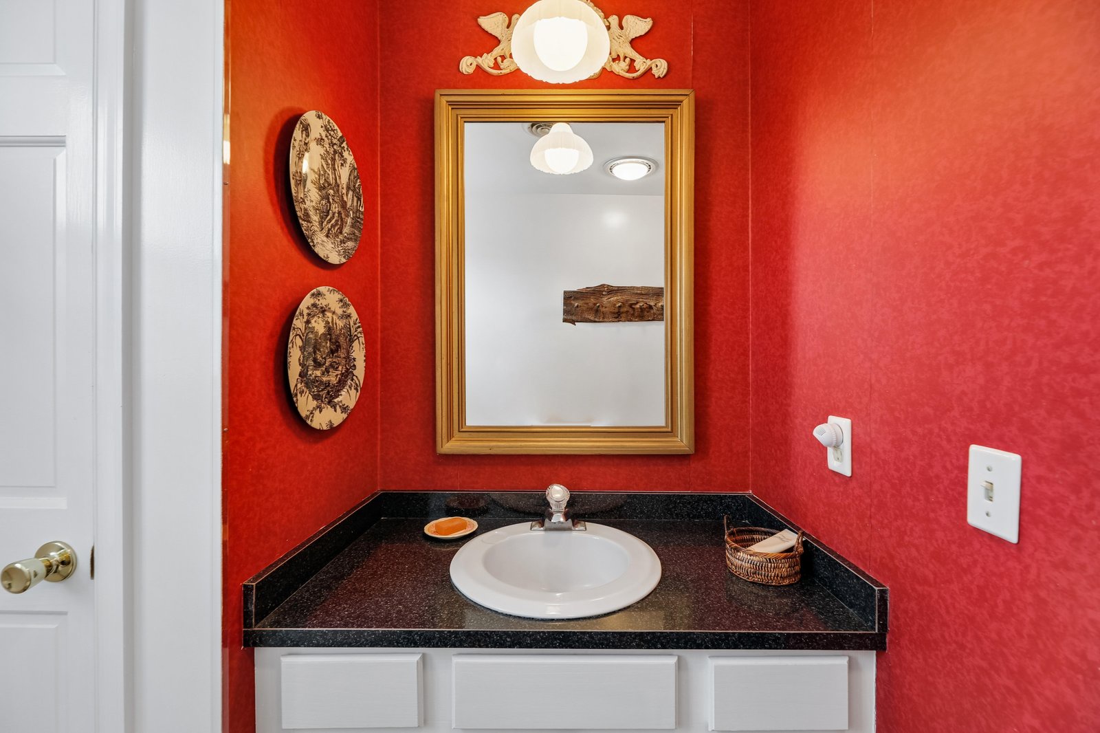 Step into your bathroom, where bold red walls and natural wood accents create a vibrant, welcoming space. The polished vanity and warm lighting make your daily routine feel like a special moment.