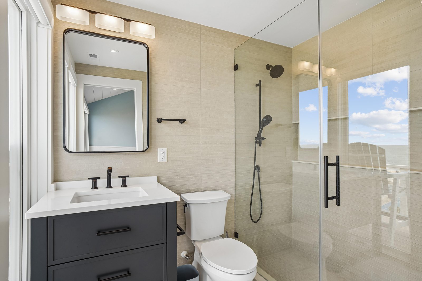 Your private bathroom features a spacious walk-in shower with sleek glass doors, neutral tile, and a vanity with modern fixtures. Natural light fills the space, creating a bright, welcoming retreat.