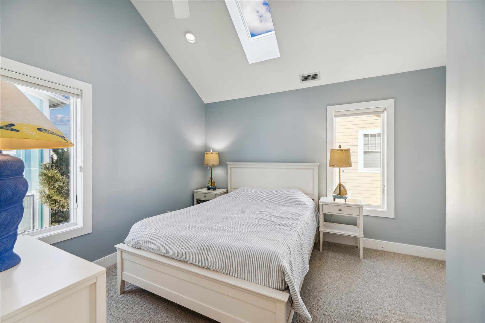 Drift off under a skylight that brings in soft natural light, while vaulted ceilings create an airy, open feel in your restful coastal bedroom retreat.