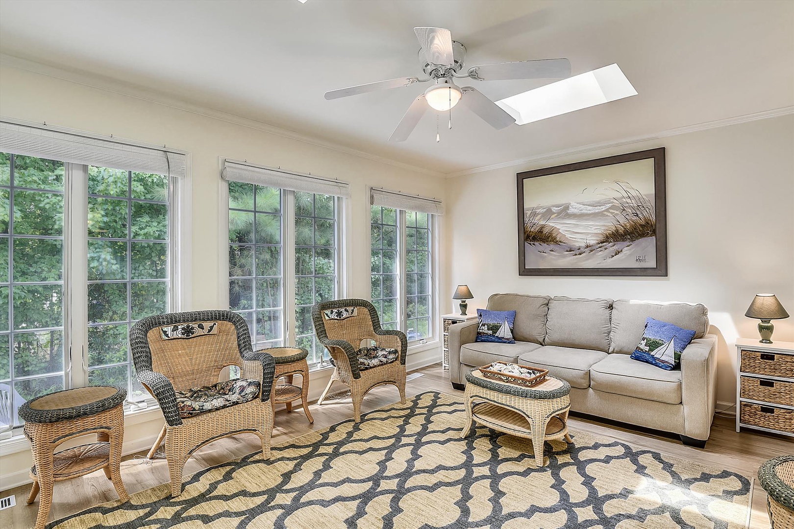 Settle into your bright, inviting living space with plush seating, coastal décor, and natural light streaming through windows overlooking peaceful greenery—perfect for relaxing after a day of exploring.