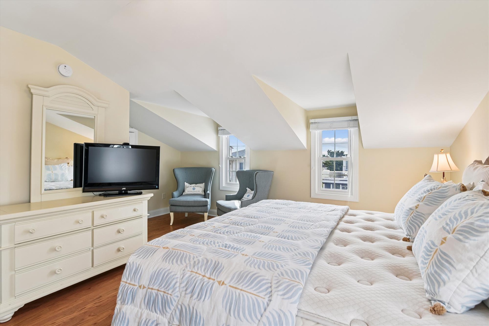Unwind in this bright bedroom with coastal charm. Comfortable bedding, charming furniture, and glimpses of sunshine create your perfect retreat.