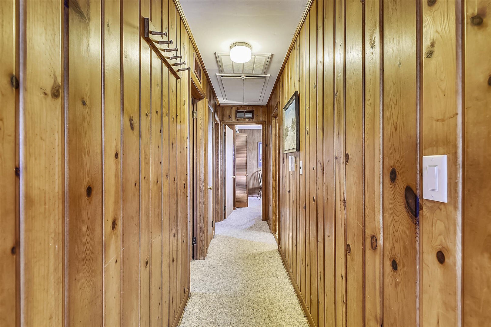 This hallway leads you from your space to other parts of the property, with warm wood paneling and soft carpet underfoot creating a cozy, cabin-like atmosphere.