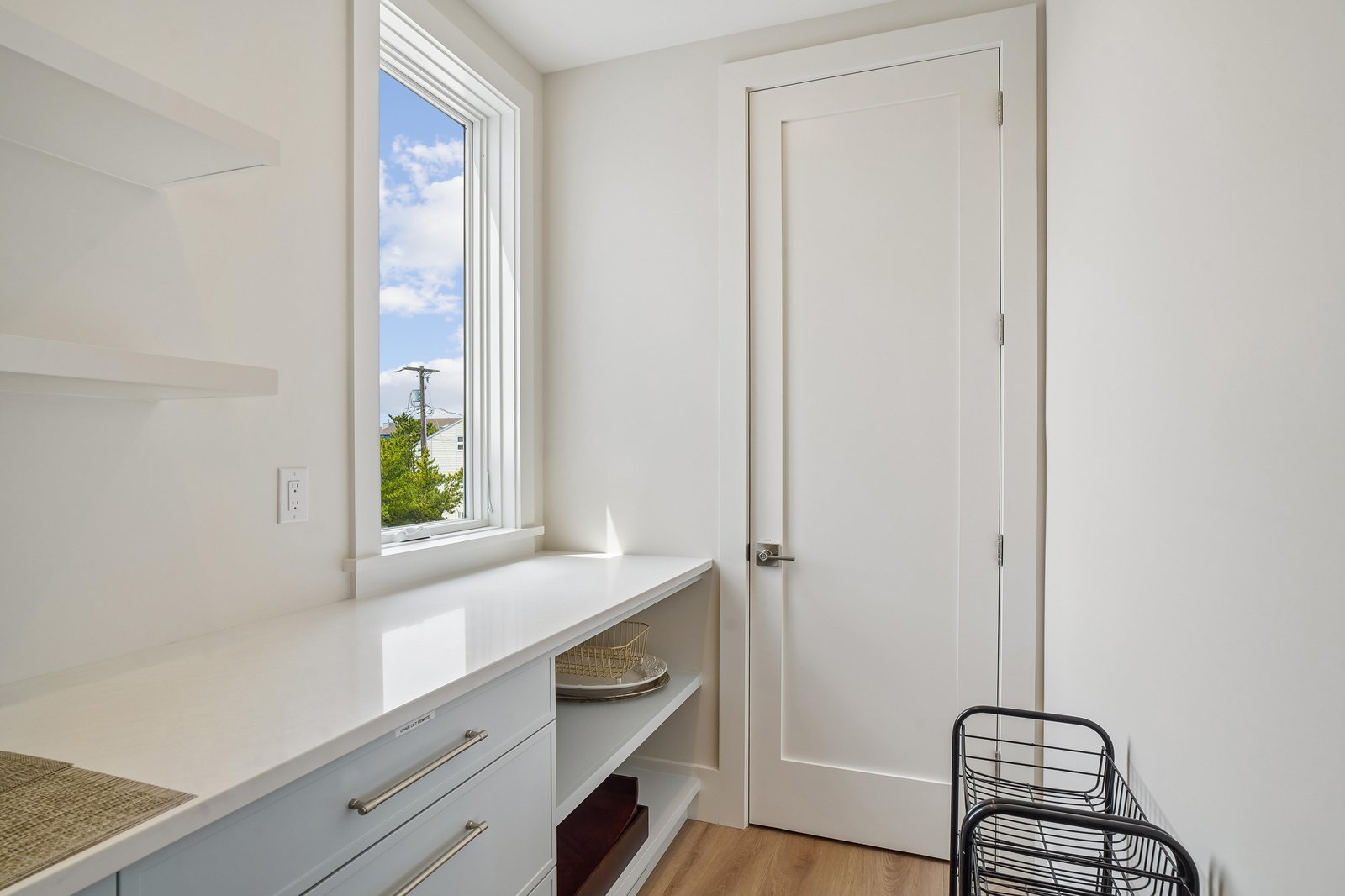 A bright laundry area featuring natural light and clean, organized storage. The window frames a pleasant neighborhood view, making everyday chores feel a bit more serene.