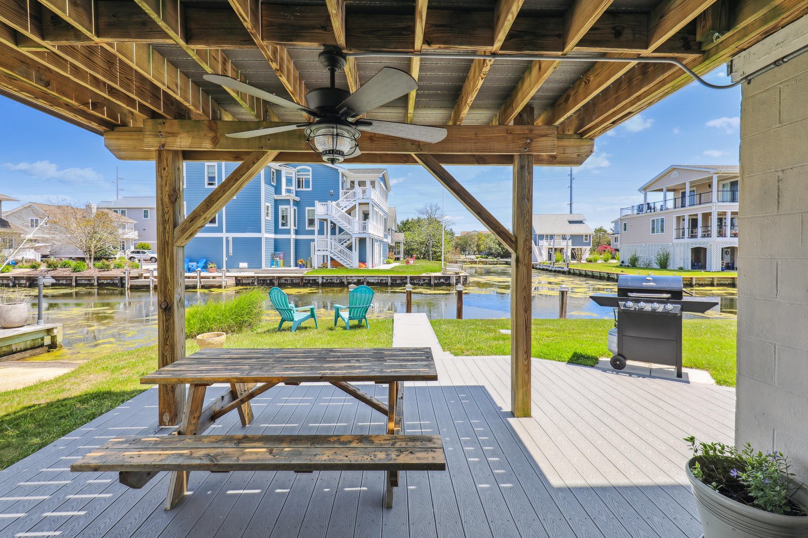 Step out onto your private covered deck with a picnic table and BBQ grill—perfect for dining alfresco while soaking in the tranquil canal views and colorful neighborhood homes.