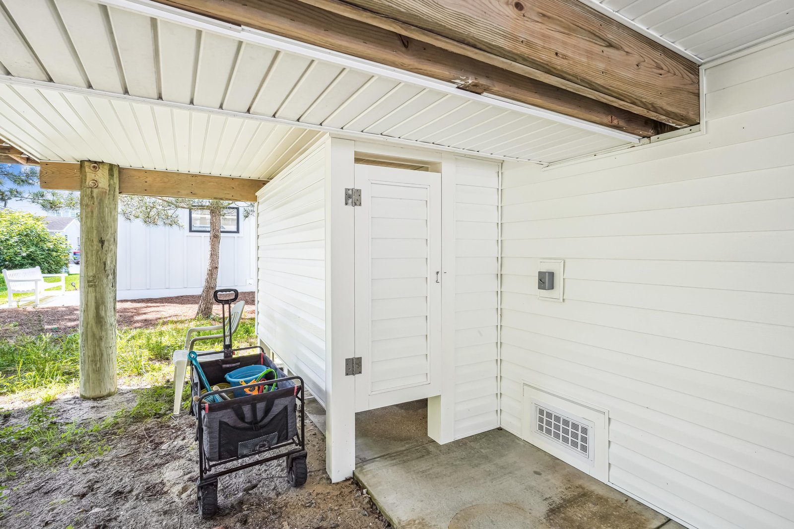 The property features a convenient covered outdoor storage area with white shiplap walls and exposed beam accents, keeping your beach gear organized and protected from the elements.