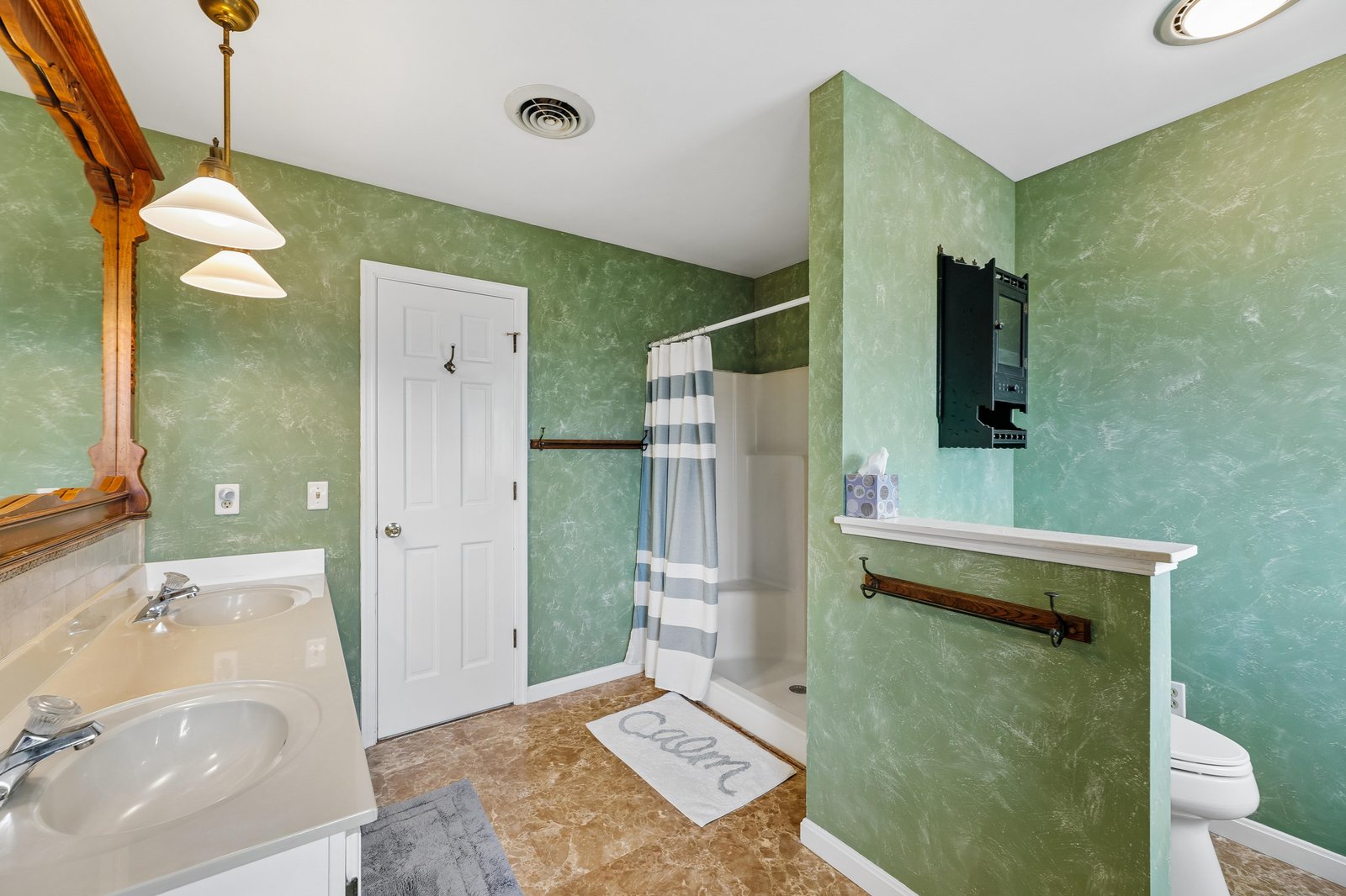 Step into your private bathroom with soothing green walls, double vanity, and a refreshing walk-in shower—your peaceful morning retreat awaits.