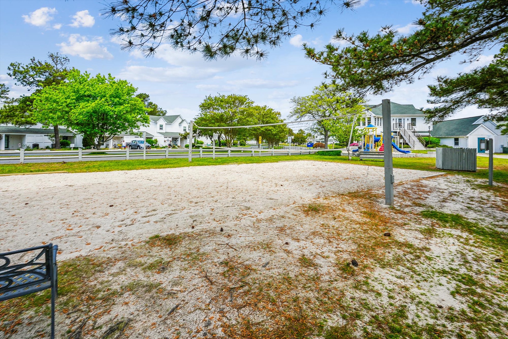 Community beach volleyball court surrounded by charming coastal homes and playground, perfect for active family fun.