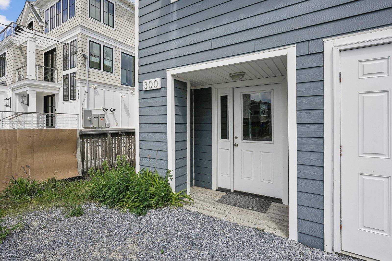 This welcoming unit entrance features clean coastal design and thoughtful details. The charming porch and nearby greenery make your arrival feel like coming home.