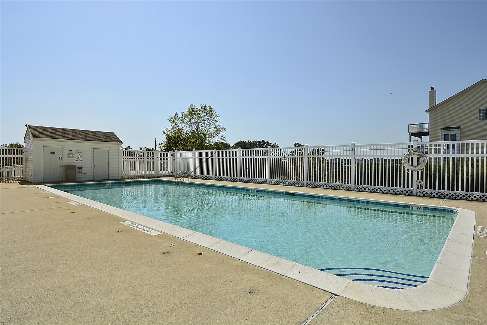 The property features a shared outdoor swimming pool surrounded by a spacious sun deck, perfect for cooling off on warm days.